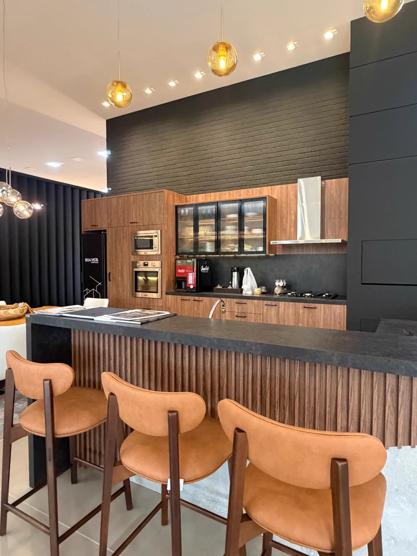 Cozinha planejada com marcenaria em madeira e bancada escura no showroom
