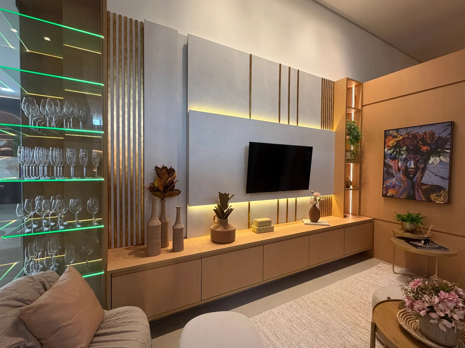 Home theater do showroom com painel iluminado, cristaleira de vidro e rack em madeira clara