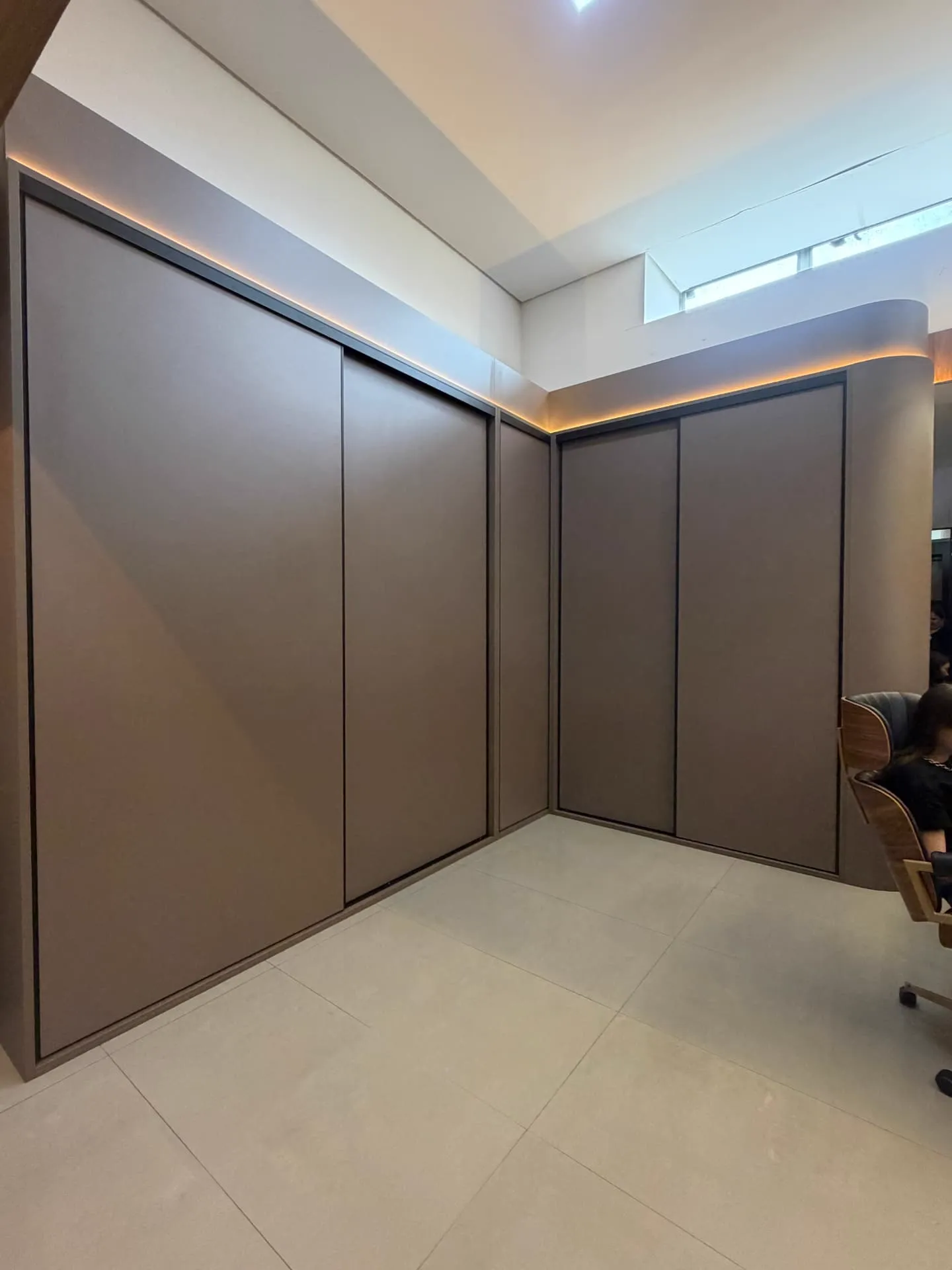 Guarda-roupa planejado de portas de correr em tom fendi com iluminação de sanca